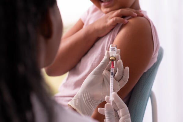 Profissional de saúde colocando vacina na seringa para aplicar em criança