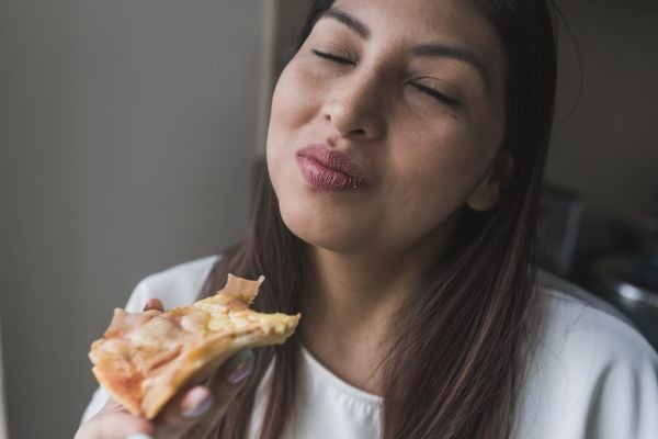 Mulher comendo uma fatia de pizza