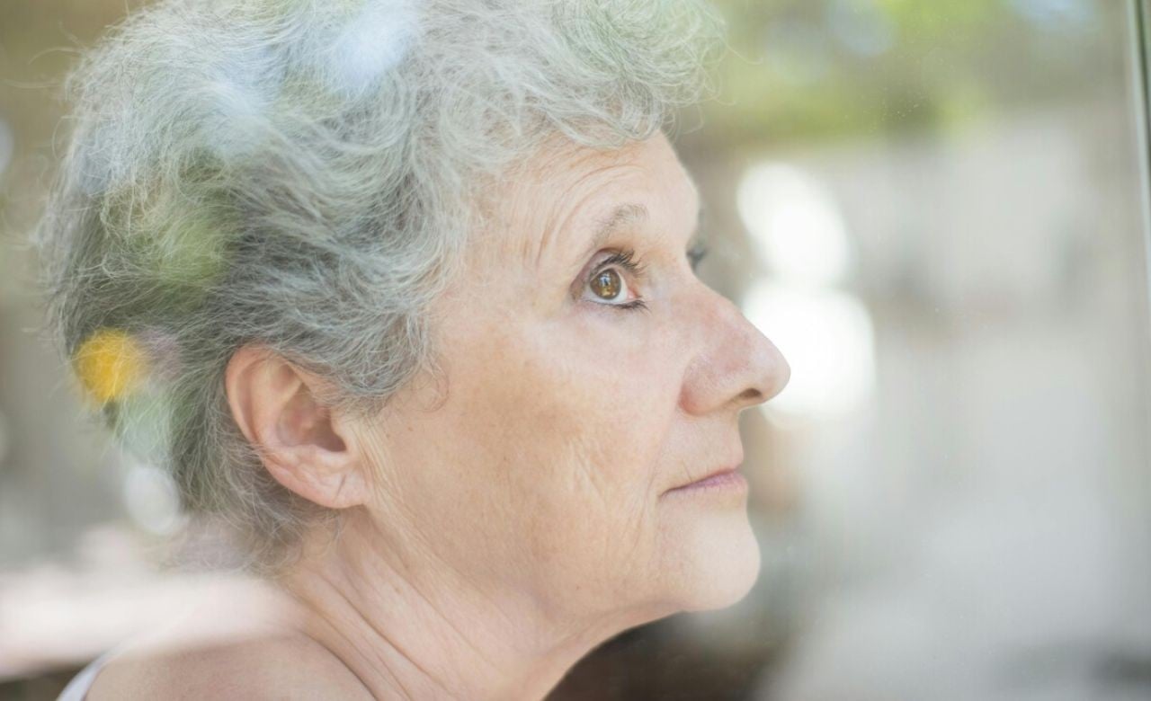 Mulher idosa observando algo em uma janela