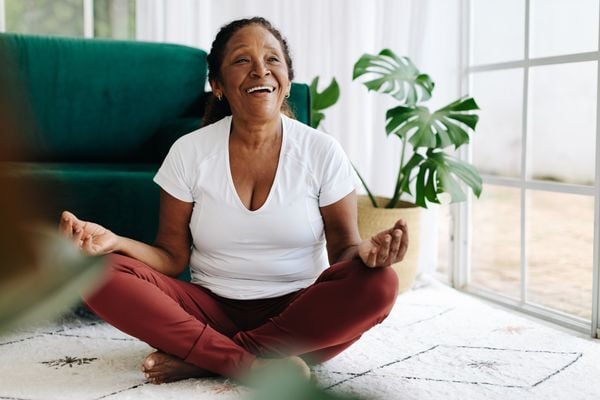 Mulher feliz meditando na posição de lótus em casa