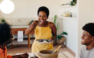 mulher comendo um prato com arroz e feijão