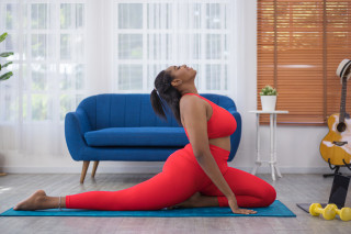 Mulher em cima de tapete azul fazendo exercícios de yoga