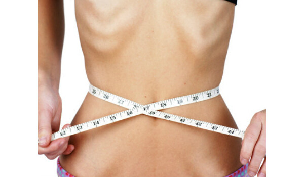 Pessoa magra medindo a cintura com fita métrica