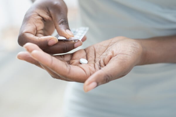 Recorte de imagem de mulher tirando um comprimido branco da cartela de remédio