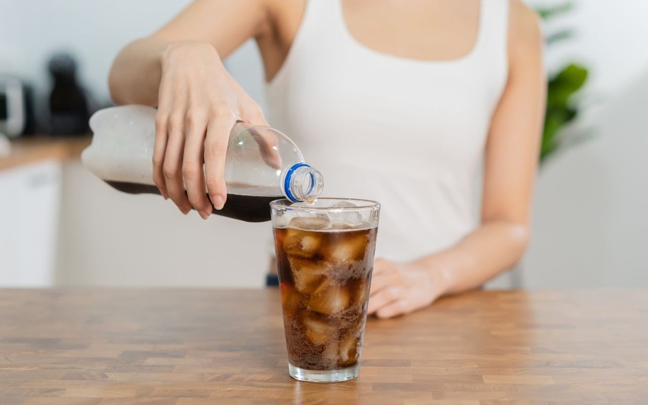 mulher servindo refrigerante em um copo