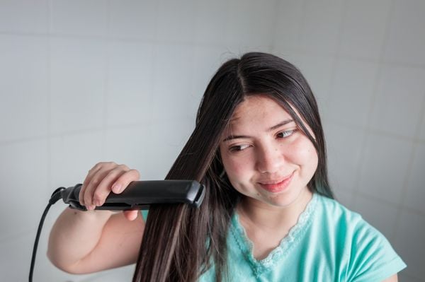 Mulher passando prancha no cabelo
