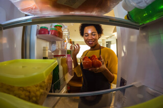 Mulher tirando tomates da geladeira