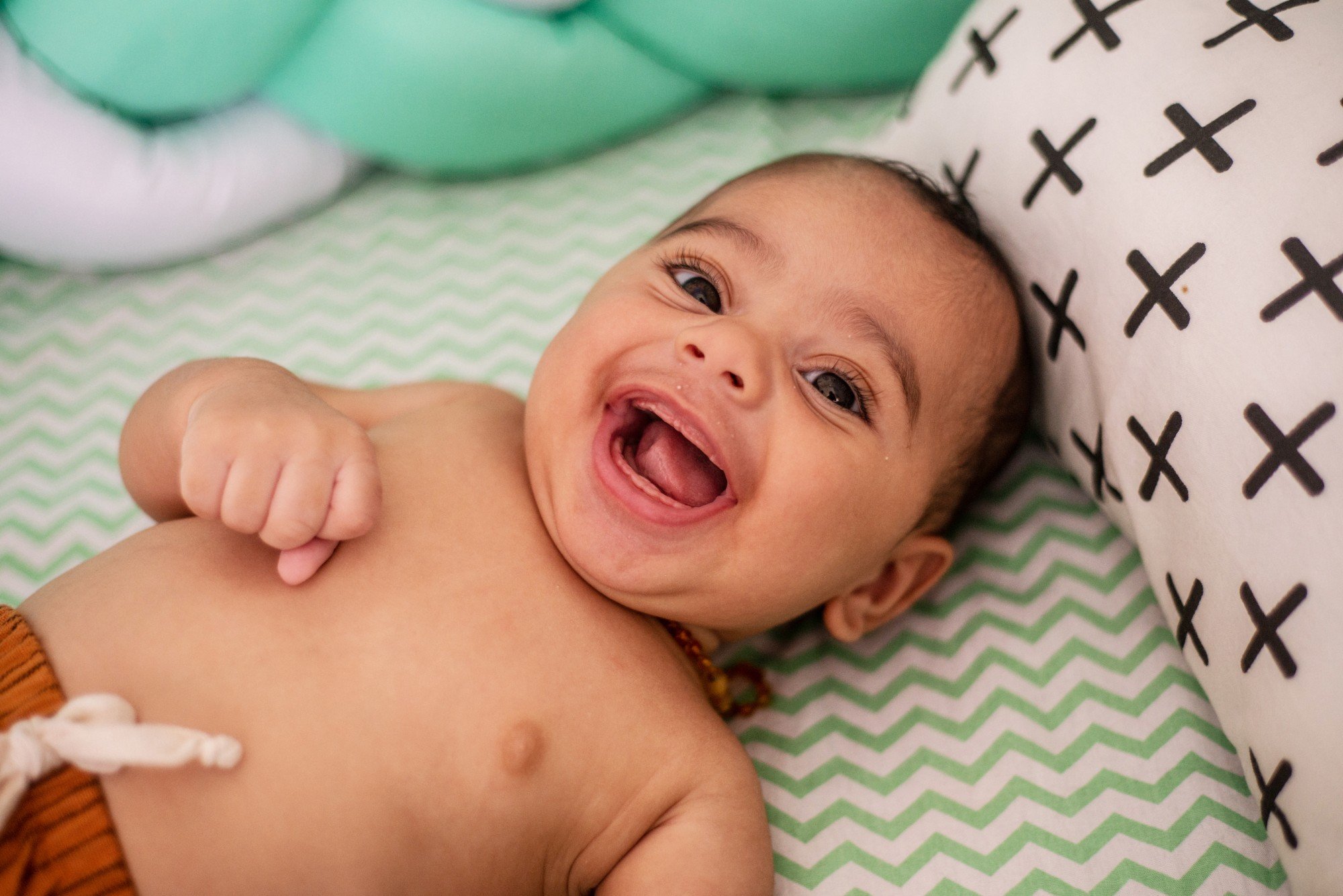 foto de bebê deitado na cama e sorrindo