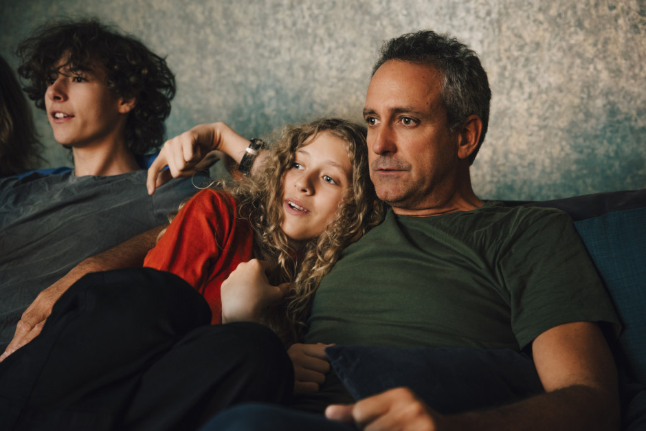 Pai e filha sentados no sofá assistindo televisão