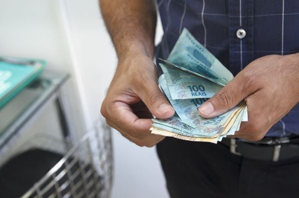 Imagem aproximada de homem contando notas de reais