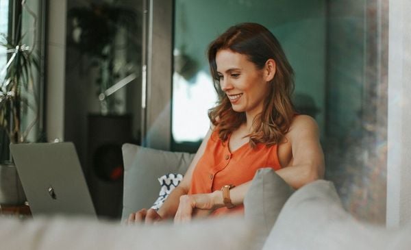 Mulher sentada em um sofá mexendo em um notebook