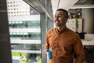 Homem jovem sorridente no escritório onde trabalha