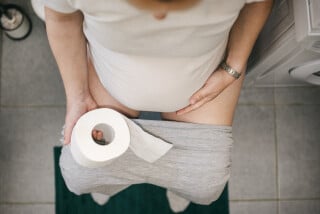 Visão de cima de uma mulher grávida usando o vaso sanitário