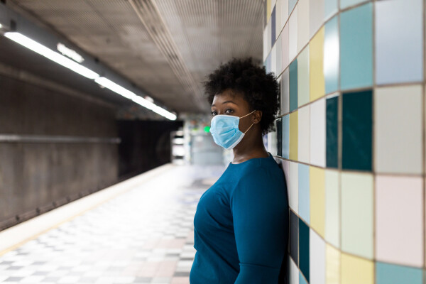 Mulher usando máscara de proteção contra COVID-19 em plataforma de metrô