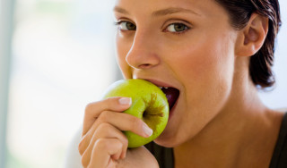 mulher comendo uma maçã verde - Foto Getty Images