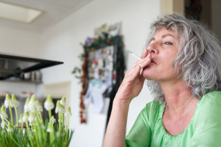 Mulher madura segurando um cigarro na boca