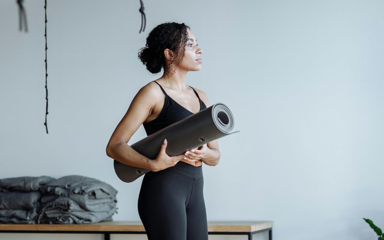 mulher segurando tapete de exercícios