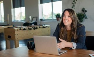 Mulher sentada em uma mesa com um notebook a frente