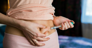Mulher com uma seringa aplicando uma injeção na barriga