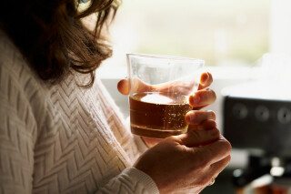 Mulher segurando um copo de bebida alcoólica na altura do peito