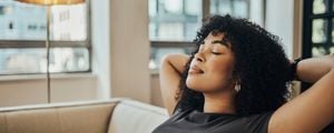 Mulher negra sentada em um sofá sozinha em casa relaxando