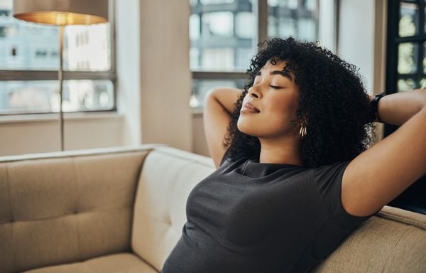 Mulher negra sentada em um sofá sozinha em casa relaxando