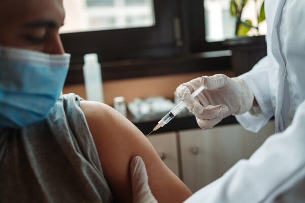 Homem recebendo vacina contra COVID-19 no braço