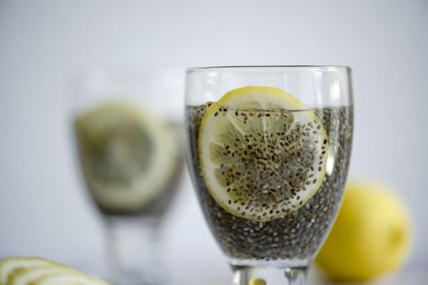 imagem aproximada de um copo com água, chia e limão. ao fundo, outro copo com os mesmos ingredientes e um limão inteiro