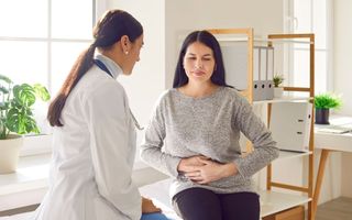 foto de médica atendendo paciente mulher com dor no estômago