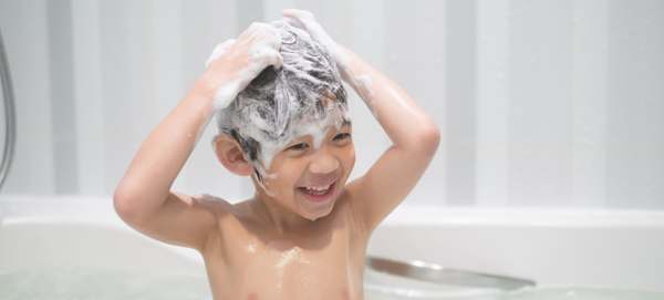 Menino de cerca de 8 anos ensaboa o cabelo durante o banho