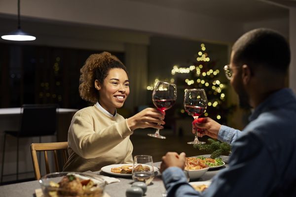 Casal de pessoas negras tendo um jantar romântico e brindando com vinho