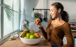 mulher segurando uma maçã na cozinha