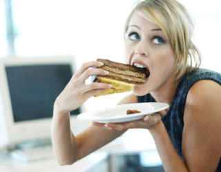 mulher comendo um bolo no trabalho