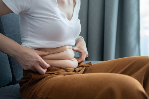 Imagem aproximada de mulher com as mãos na barriga