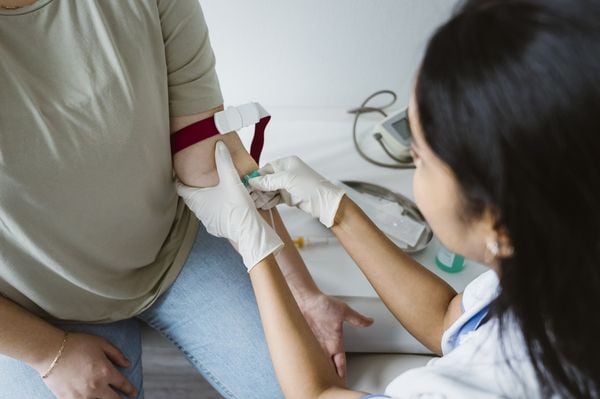 imagem aproximada de uma médica colocando uma agulha no braço de uma paciente para um exame de sangue