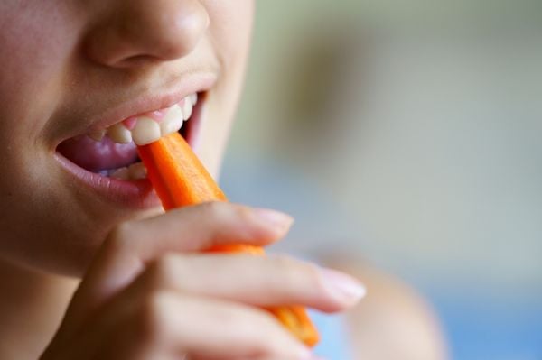 Imagem aproximada de mulher comendo cenoura crua