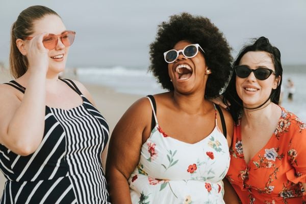 três mulheres sorrindo na praia