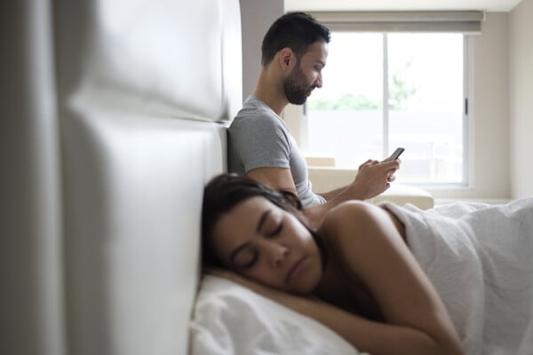 Mulher dormindo com homem mexendo no celular