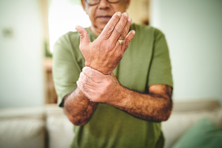 Homem idoso com a mão segurando o pulso sentindo dor
