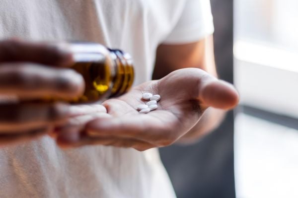 Imagem aproximada de mãos masculinas segurando medicamentos