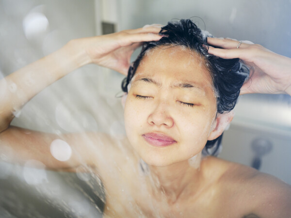 Mulher asiática lavando o cabelo no chuveiro