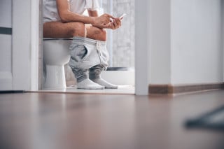 Homem sentado no vaso sanitário
