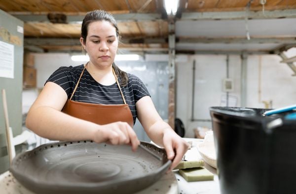 mulher faz buracos na tigela de barro em uma fábrica de cerâmica
