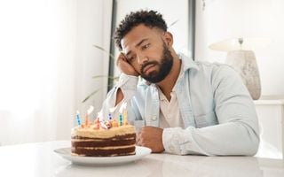 homem triste olhando para um bolo de aniversário