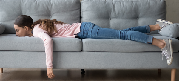 Mulher jovem deitada de bruços em um sofá, descansando