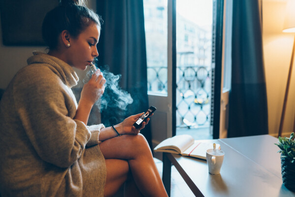 Mulher sentada com um cigarro na boa e um celular na mão