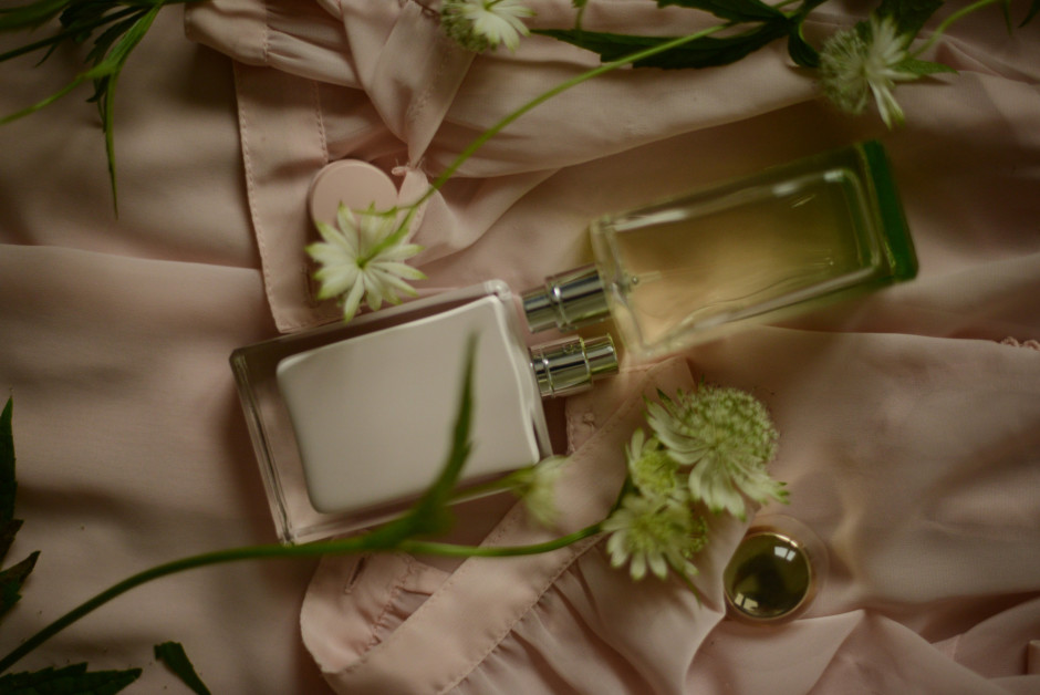Frascos de perfume em lençol claro e detalhes de flores