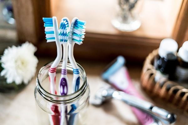 Três escovas de dente em um pote de vidro