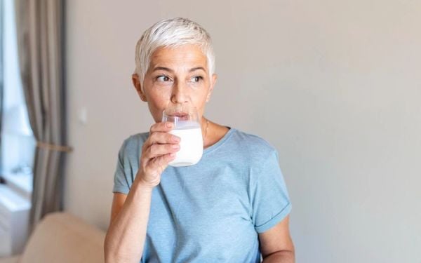 mulher de 50+ bebendo um copo de leite