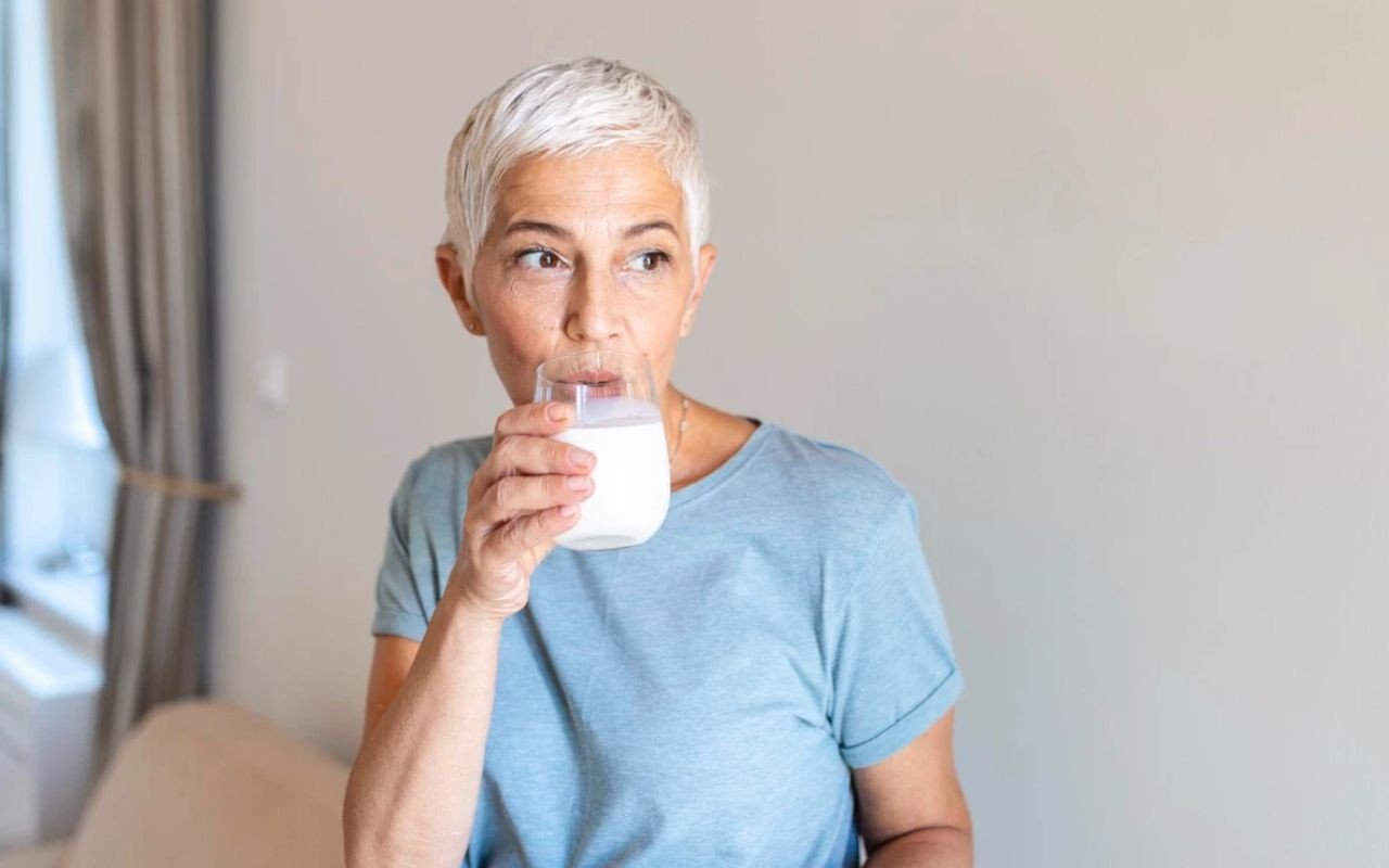 mulher de 50+ bebendo um copo de leite